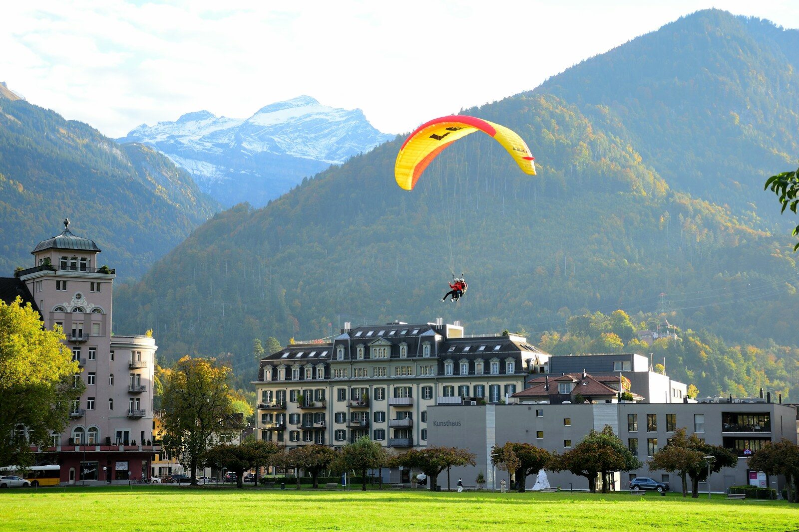a paraglider is flying over a city with mountains in the background